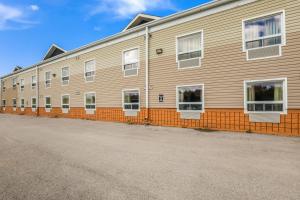 a tan building with white windows and an orange fence at Knights Inn Orillia in Orillia