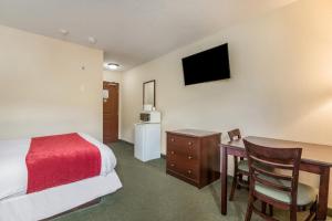 a hotel room with a bed and a desk with a table at Knights Inn Orillia in Orillia