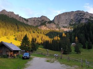 a truck parked next to a cabin in the mountains at Apartments Pod macesnovo streho in Solčava