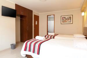 um quarto de hotel com duas camas e uma televisão em Mauri em Huánuco