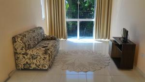 a living room with a couch and a window at Apt. mobiliado em Coroa Vermelha in Santa Cruz Cabrália