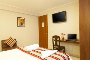 um quarto de hotel com uma cama e uma secretária com um computador portátil em Mauri em Huánuco