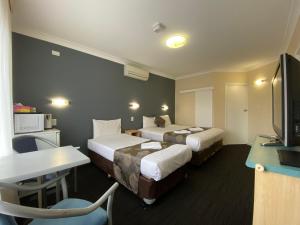 
a hotel room with two beds and a television at Welcome Inn 277 in Adelaide
