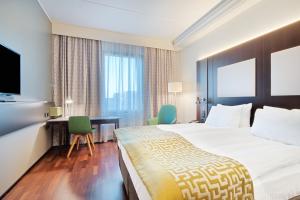 a hotel room with a bed and a desk and a television at Holiday Inn Helsinki West - Ruoholahti by IHG in Helsinki +80 photos