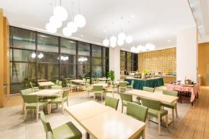a restaurant with tables and chairs and windows at Holiday Inn Express Haikou West Coast, an IHG Hotel in Haikou
