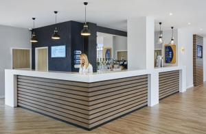 a woman standing at a bar in a restaurant at Holiday Inn Express Grimsby, an IHG Hotel in Grimsby