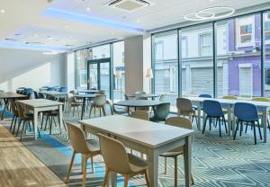a cafeteria with tables and chairs and windows at Holiday Inn Express Grimsby, an IHG Hotel in Grimsby