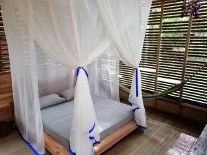 a bed in a room with white curtains and a window at Palmayacu - Refugio Amazónico in Leticia