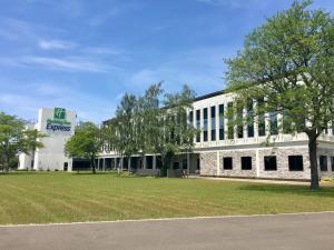 a large white building with a tree in front of it at Holiday Inn Express - Grand Island by IHG in Niagara Falls