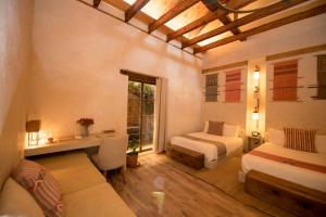 a bedroom with a bed and a couch and a window at Casa Lum in San Cristóbal de Las Casas