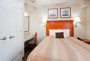 a bedroom with a bed with a wooden headboard and a desk at Candlewood Suites Jacksonville by IHG in Jacksonville