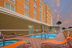 une piscine dans un hôtel avec des chaises et un bâtiment dans l'établissement Holiday Inn Jacksonville E 295 Baymeadows, an IHG Hotel, à Jacksonville