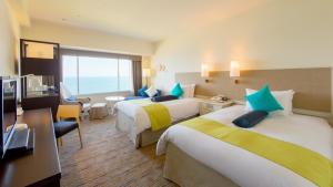 een hotelkamer met 2 bedden en een televisie bij ANA Holiday Inn Resort Miyazaki, an IHG Hotel in Miyazaki