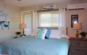 a bedroom with a blue bed with pillows and a window at Latitude 26 Waterfront Boutique Resort - Bonita Springs in Bonita Springs