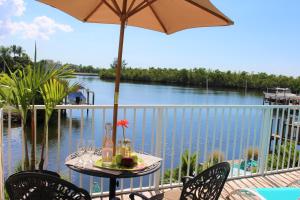 a table with an umbrella on a balcony overlooking a river at Latitude 26 Waterfront Boutique Resort - Bonita Springs in Bonita Springs