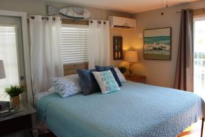 a bedroom with a bed with blue pillows and a window at Latitude 26 Waterfront Boutique Resort - Bonita Springs in Bonita Springs