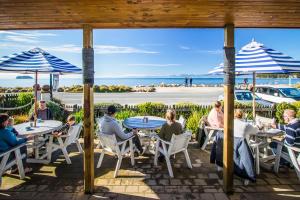 a group of people sitting at tables with umbrellas at Aroha Anchor Apartment in Motueka