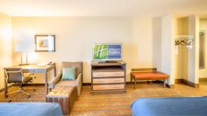 a hotel room with a television and a desk with a couch at Holiday Inn Express Wichita South, an IHG Hotel in Wichita