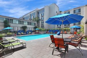 einen Pool mit einem Tisch und Stühlen sowie einem blauen Sonnenschirm in der Unterkunft Holiday Inn Hotel & Suites Anaheim, an IHG Hotel in Anaheim