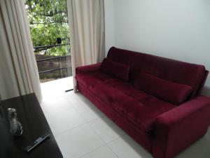 un divano rosso in un soggiorno con finestra di Aconchego e Requinte no Centro a Petrópolis