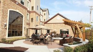 a patio with people sitting at tables and an umbrella at Staybridge Suites Lincoln North East, an IHG Hotel in Lincoln