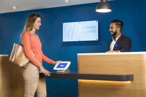 Un uomo e una donna che stringono la mano a un bancone di Holiday Inn Express Park Royal, an IHG Hotel a Londra