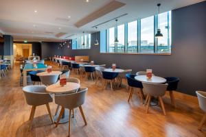 un restaurante con mesas, sillas y ventanas en Holiday Inn Express - London Heathrow T4 by IHG, en Hillingdon