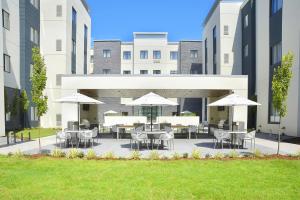 un patio con mesas, sillas y sombrillas en Staybridge Suites - Little Rock - Medical Center, an IHG Hotel en Little Rock