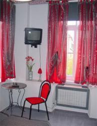 a room with a red chair and a table and a tv at Hotel zur Eiche in Oberthal
