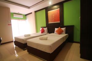 two beds in a room with green walls at The Grand Pinnacle Bangkok Airport in Lat Krabang