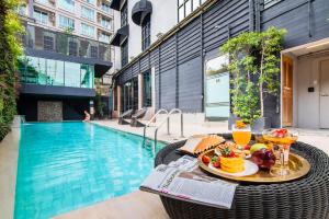 a table with food and drinks next to a swimming pool at Metropole Bangkok in Bangkok