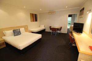 a hotel room with two beds and a table at Red Bridge Motor Inn in Woombye