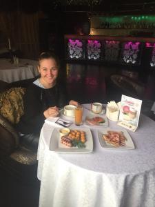 a woman sitting at a table with a plate of food at Moy Uyutniy Dom Hotel in Kurgan