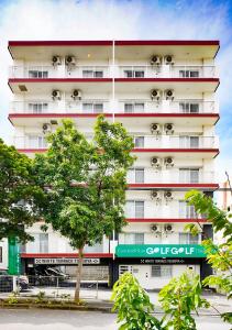ein hohes weißes Gebäude mit einem Baum davor in der Unterkunft Condominium GOLF GOLF Tsuboya in Naha