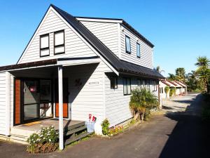 una casa blanca con techo negro en Tairua Shores Motel, en Tairua