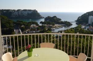 a table on a balcony with a view of the ocean at Menorca Bonavista in Cala Galdana