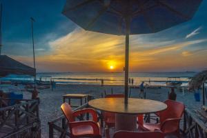 un tavolo con sedie e un ombrellone in spiaggia di COCONUT BEACH LODGE a Trincomalee