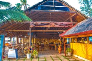 un restaurante con techo con mesas y sillas en COCONUT BEACH LODGE en Trincomalee