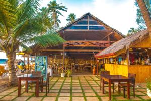 un restaurante en la playa con mesas y sillas en COCONUT BEACH LODGE, en Trincomalee