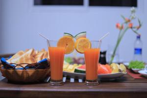 dwa kieliszki soku pomarańczowego obok kosza owoców w obiekcie Star Beach Guest House w Negombo