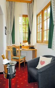 uma sala de estar com um sofá, uma cadeira e uma secretária em Alpenhof em Gauting