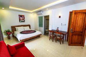 1 dormitorio con cama, escritorio y sofá rojo en Boutique Hotel La Villa, en Nha Trang 80 fotos más