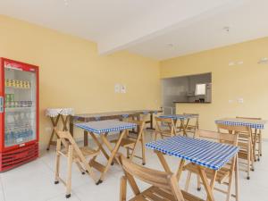 a cafeteria with tables and chairs and a refrigerator at Hotel Jardim Emilia Sorocaba in Sorocaba