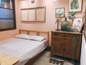 ein Schlafzimmer mit einem Bett und einer Holzkommode in der Unterkunft 醒覺旅人-訂房後需聯繫轉帳 in Tainan