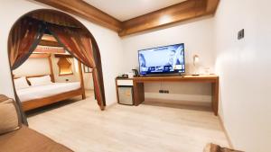 a room with a television on a desk with a bed at Big Tree Old Town Hotel in Chiang Mai