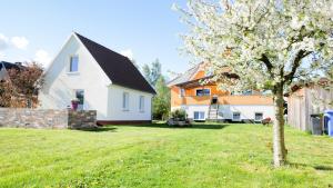 a white house with a tree in the yard at Ferienhaus in Kuehlungsborn in Kühlungsborn