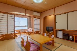 uma sala de estar com uma mesa e cadeiras e uma televisão em Jakomaru Park Tsuda em Sanuki