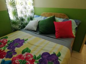 uma cama com almofadas coloridas em cima em Laly's B8 cozy Vacation Townhouse - 10km to SBMA em Olongapo