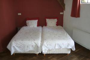 two beds in a bedroom with red walls at B&B De Leeghpoel in Rumpt