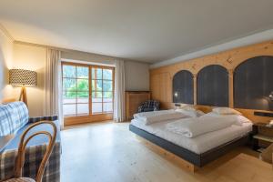 a bedroom with a bed and a desk and a window at Romantik Hotel Post in Nova Levante